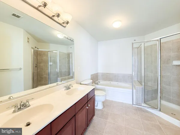 a spacious bathroom with a bathtub shower sink mirror and toilet