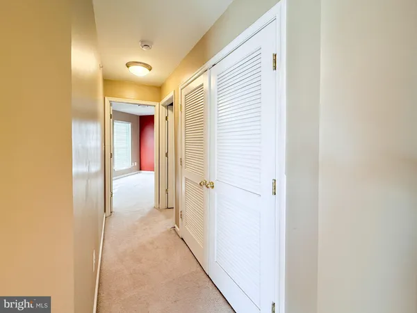 a view of a hallway with wooden floor and a bathroom