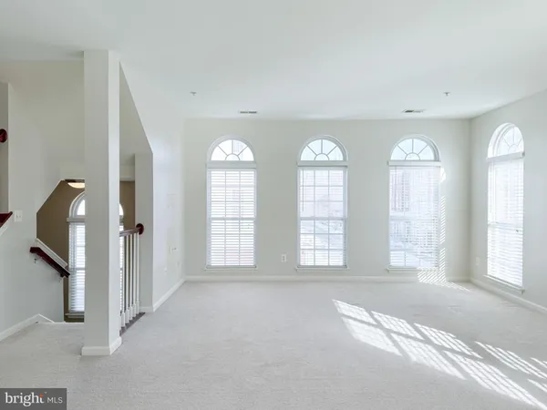 a view of an empty room with two windows and a chandelier