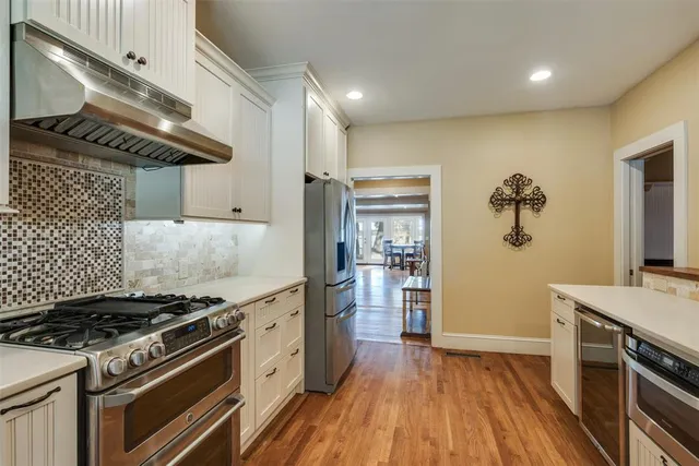 a kitchen with a sink cabinets wooden floor and stainless steel appliances