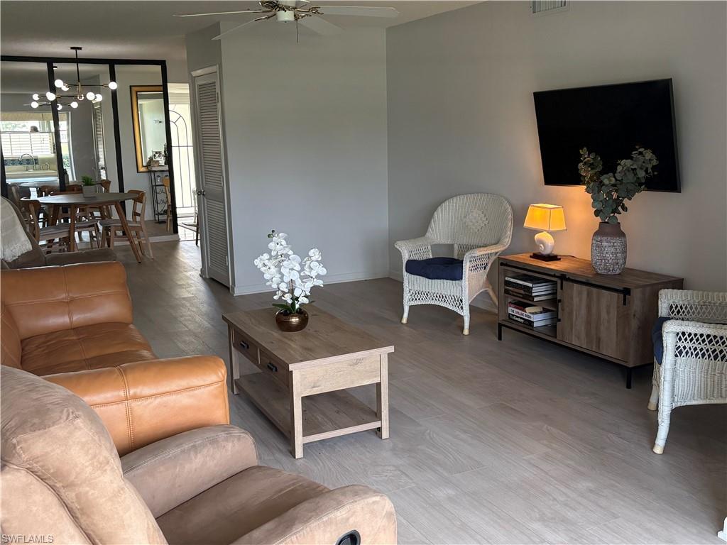 315 St Andrews Boulevard, Unit A2 Naples, FL 34113 - Photo 13 of 17 Living area with suspended lighting, wood finished floors, and a ceiling fan