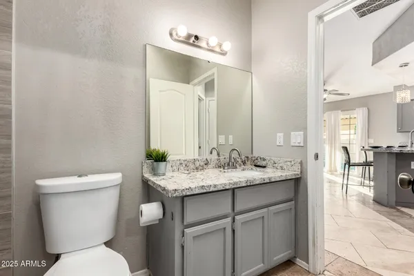 a bathroom with a granite countertop toilet a sink and a mirror