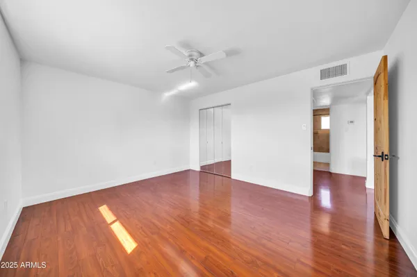 an empty room with wooden floor fan and windows