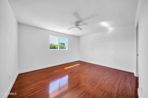 a view of an empty room with window and wooden floor