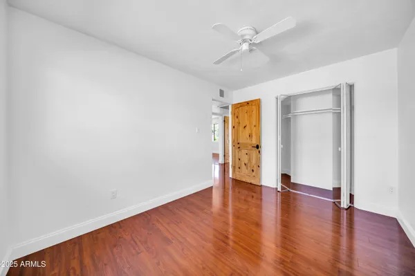 an empty room with wooden floor ceiling fan and windows