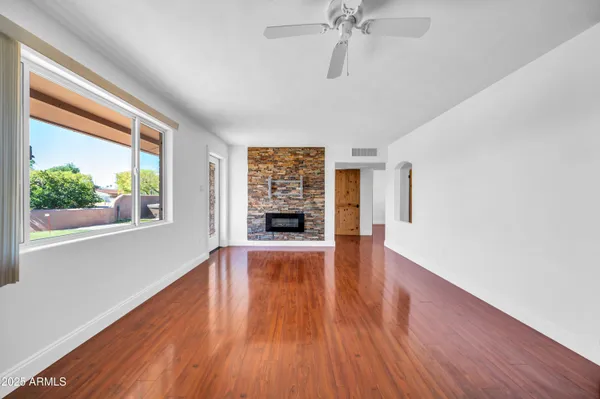 a view of an empty room with window and wooden floor
