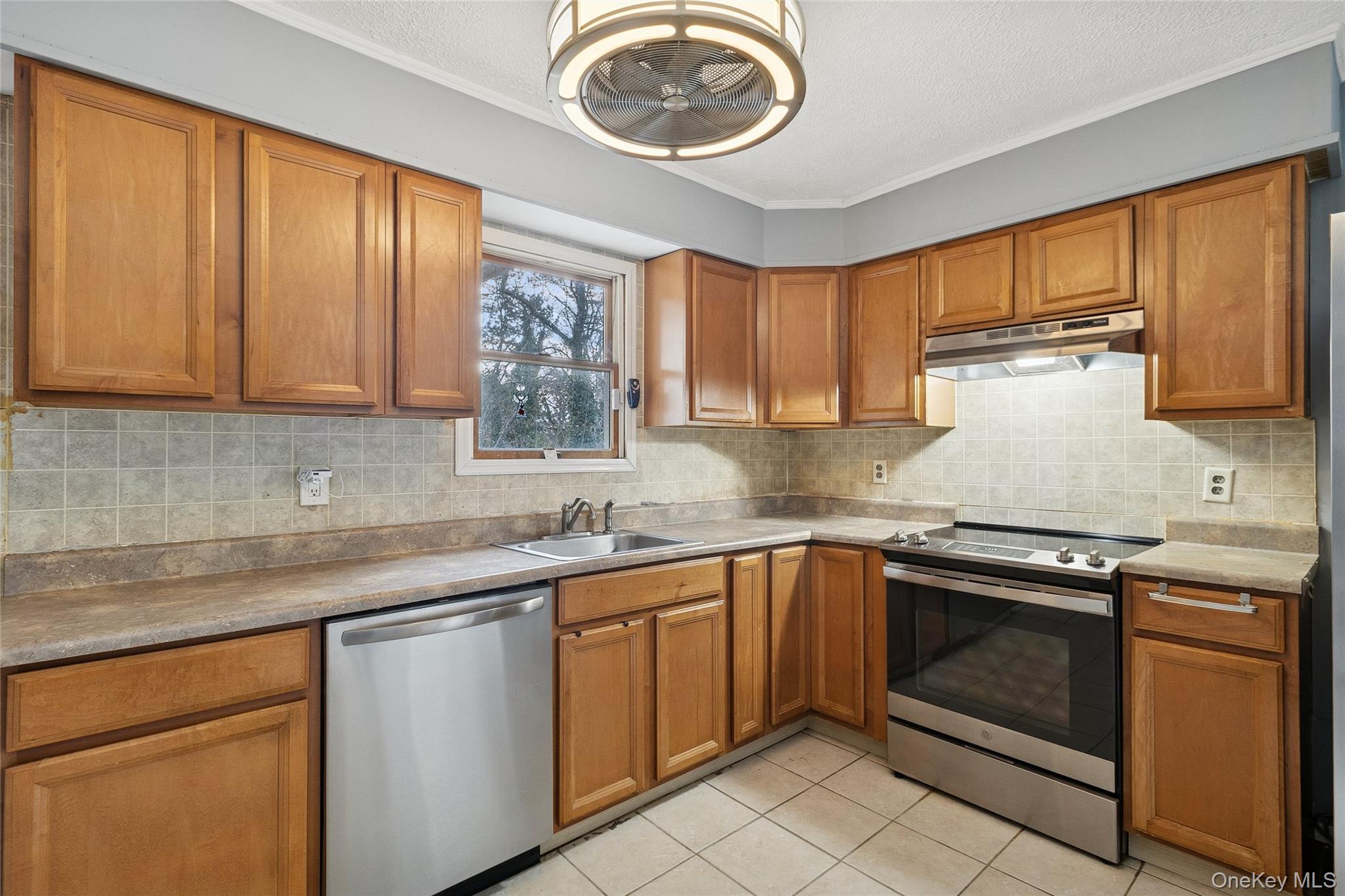 361 Decatur Avenue Shirley, NY 11967 - Photo 29 of 33 Kitchen featuring stainless steel appliances, brown cabinetry, tasteful backsplash, and under cabinet range hood