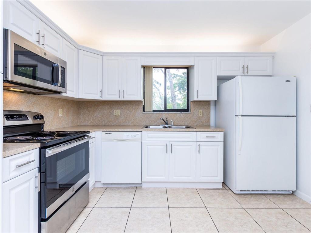 16243 Saddle Club Road, Unit 204 Weston, FL 33326 - Photo 5 of 48 a kitchen with white cabinets and white appliances