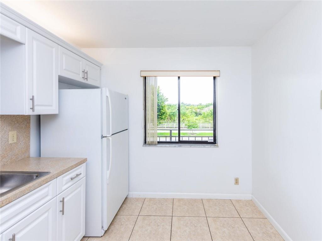 16243 Saddle Club Road, Unit 204 Weston, FL 33326 - Photo 7 of 48 a view of a kitchen with white cabinets and refrigerator