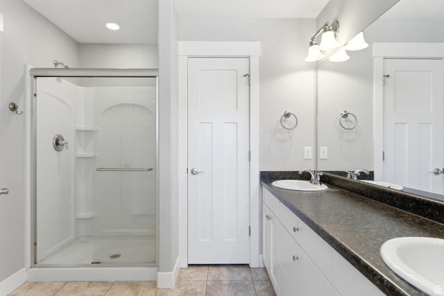 1614 Aspen Loop Provo, UT 84606 - Photo 23 of 47 Bathroom featuring a glass-enclosed shower, dual vanity with undermount sinks, and a dark countertop