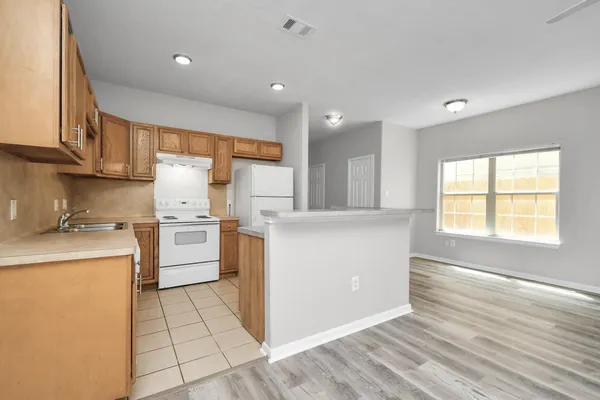 a kitchen with a sink a stove a refrigerator and white cabinets