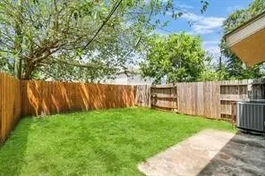 a view of a backyard with wooden fence and a large tree