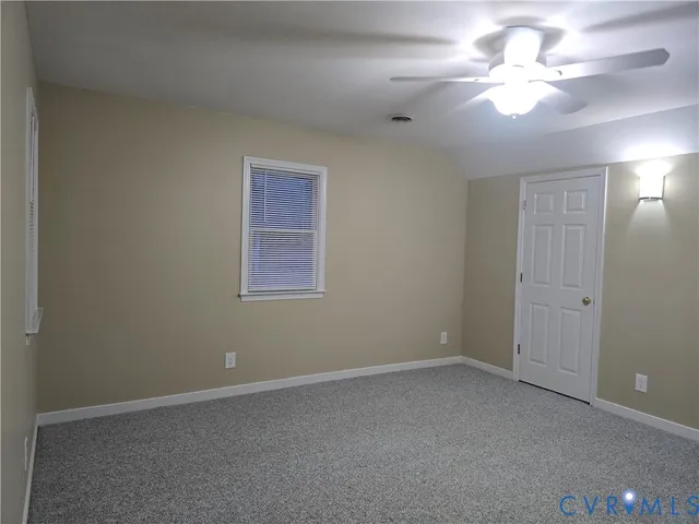 an empty room with a chandelier fan and windows
