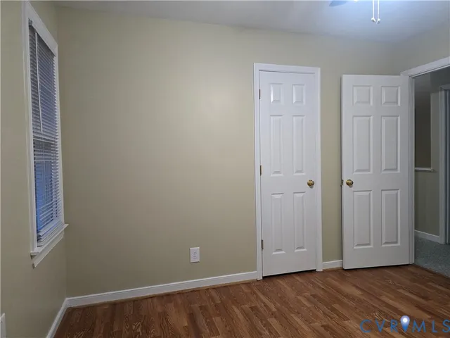 a view of an empty room with wooden floor and closet