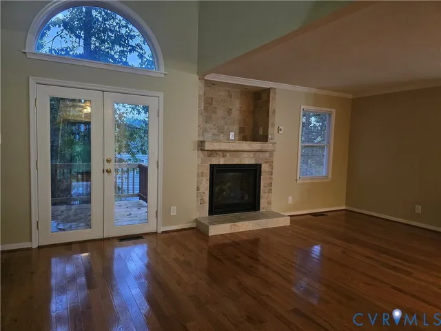 an empty room with wooden floor a fireplace and windows
