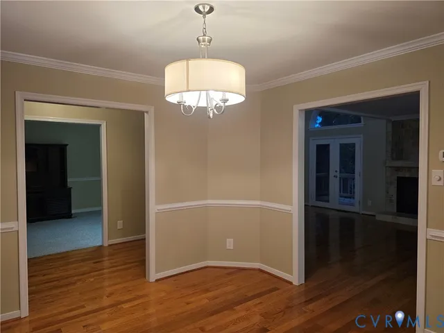 an empty room with wooden floor chandelier and windows
