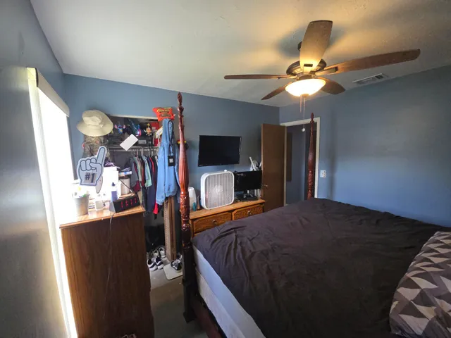 a bedroom with a bed and a flat tv screen on the dresser