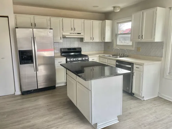 a kitchen with stainless steel appliances granite countertop a refrigerator a sink a stove a microwave and wooden cabinets