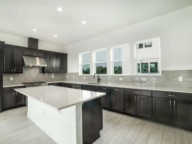 a large kitchen with stainless steel appliances granite countertop a sink and a stove