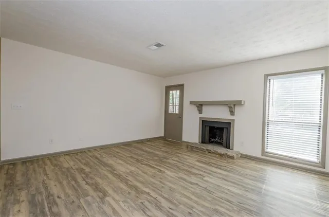 a view of empty room with wooden floor and fireplace