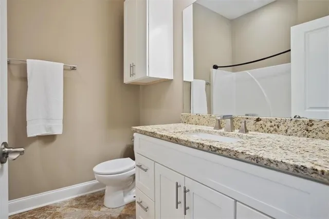 a bathroom with a granite countertop sink a toilet and a mirror