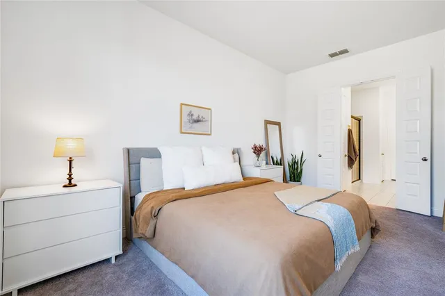 a bedroom with a bed and a lamp on dresser