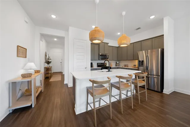 a kitchen with stainless steel appliances a dining table chairs stove and refrigerator
