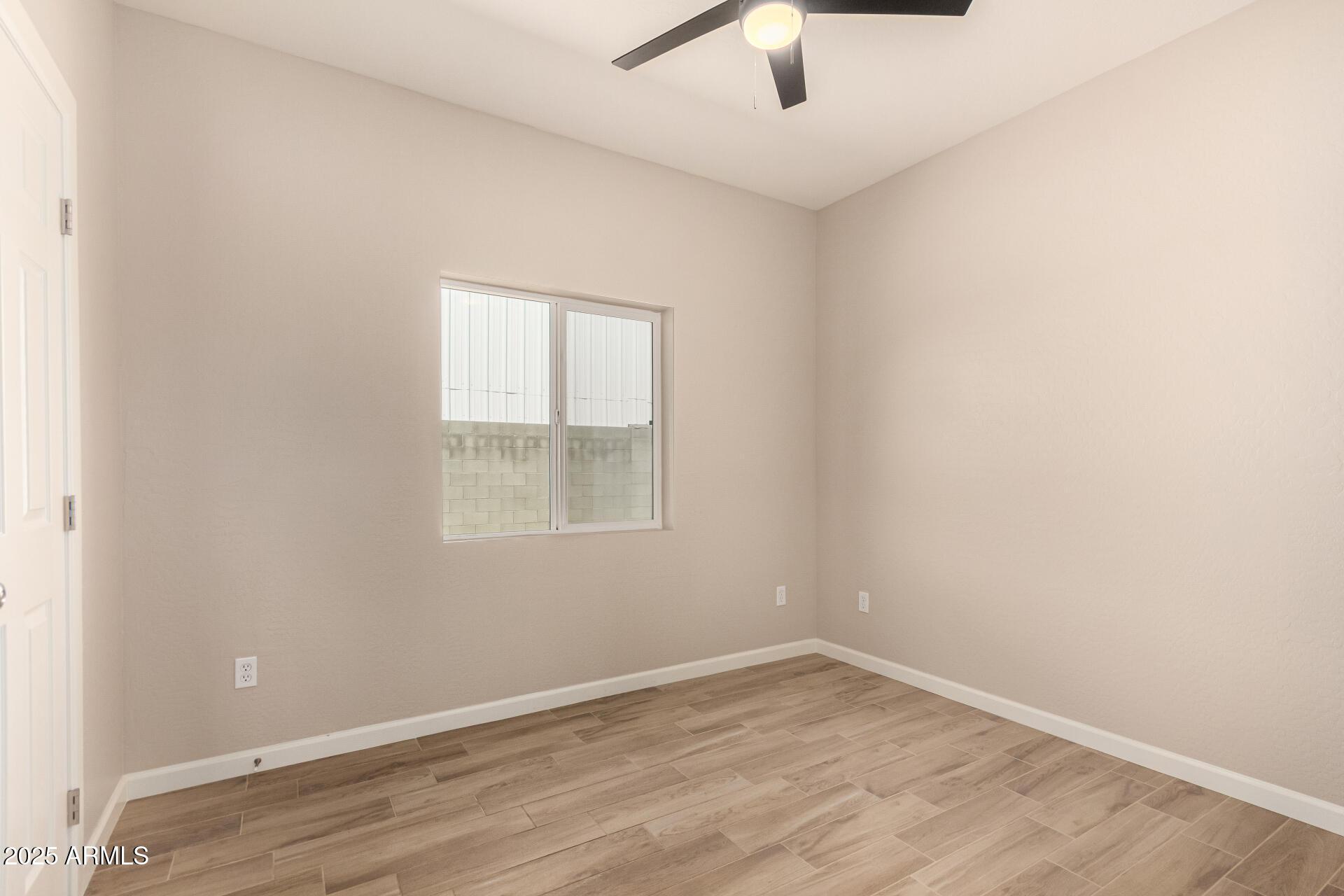 2746 West Pima Street, Unit 2 Phoenix, AZ 85009 - Photo 19 of 24 an empty room with a window and a ceiling fan