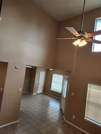 en empty room with wooden floor and fan