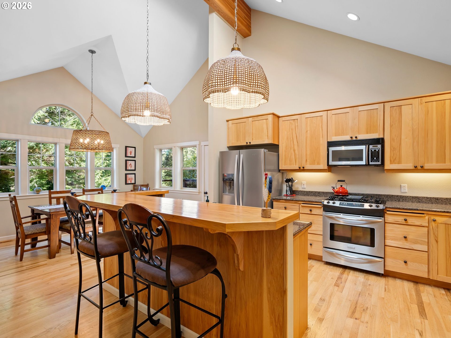 10 Big Tree Road Gleneden Beach, OR 97388 - Photo 13 of 48 a kitchen with stainless steel appliances granite countertop a stove a refrigerator a microwave a dining table and chairs with wooden floor