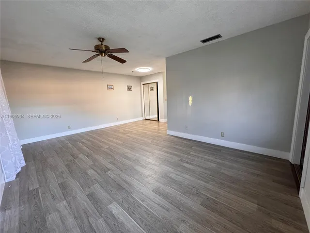 a view of a big room with wooden floor ceiling fan and windows
