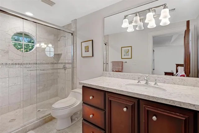 a bathroom with a granite countertop sink a large mirror a toilet and a shower