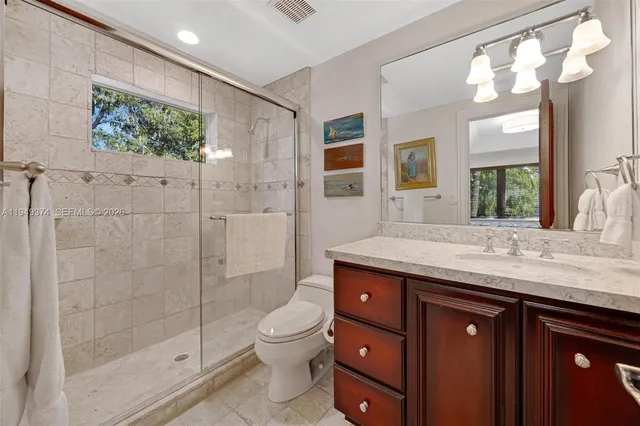 a bathroom with a granite countertop sink a toilet and shower