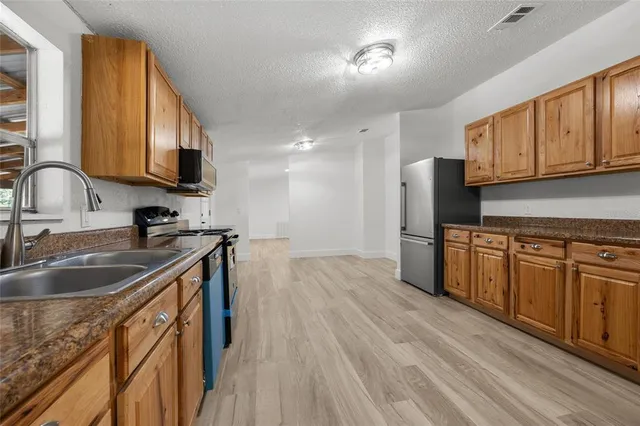 a kitchen with stainless steel appliances granite countertop a sink stove and refrigerator