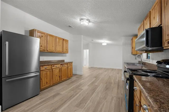 a kitchen with granite countertop a refrigerator stove top oven and sink