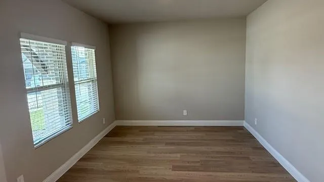 a view of an empty room with wooden floor and a window