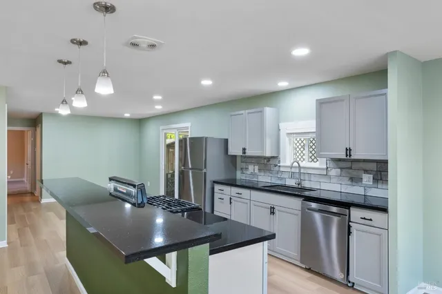 a kitchen with stainless steel appliances granite countertop a sink a stove a refrigerator and island