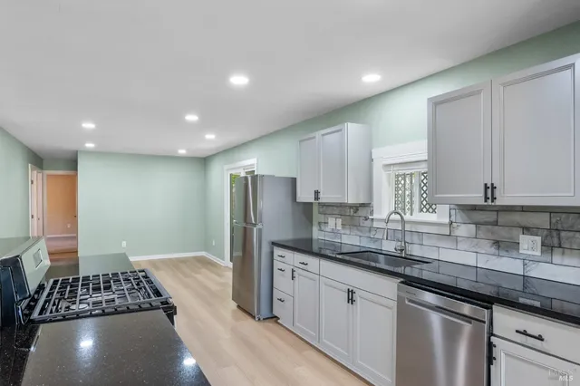 a kitchen with stainless steel appliances granite countertop a sink stove and cabinets