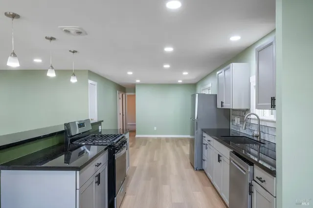 a kitchen with granite countertop a sink stove and cabinets