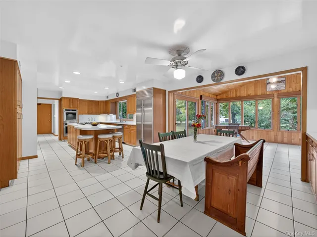 a dining hall with stainless steel appliances a dining table and chairs with a large window