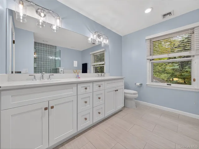 a spacious bathroom with double vanity sink a large mirror a bathtub and window
