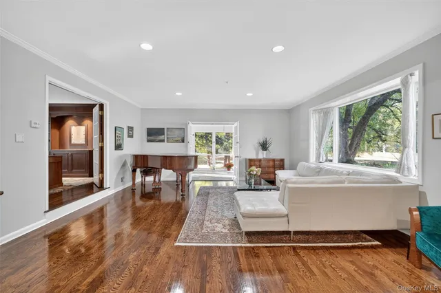 a living room with furniture a large window and wooden floor