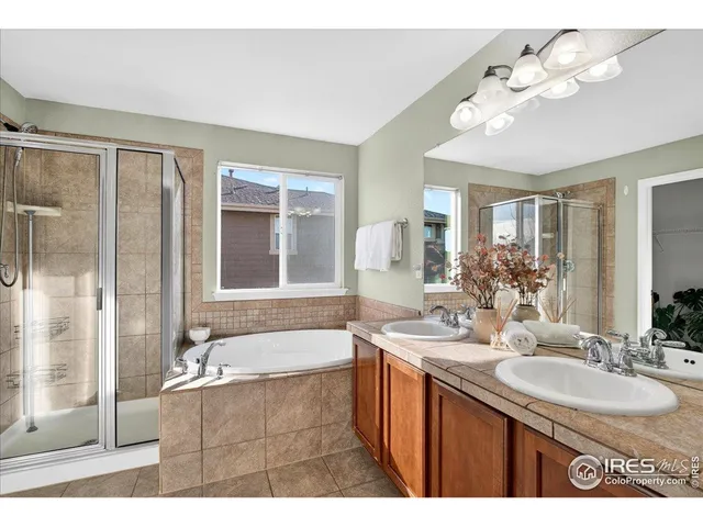 a bathroom with a tub a double vanity sink a mirror and a shower