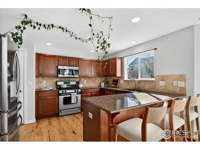 a kitchen with stainless steel appliances granite countertop a sink a stove and refrigerator