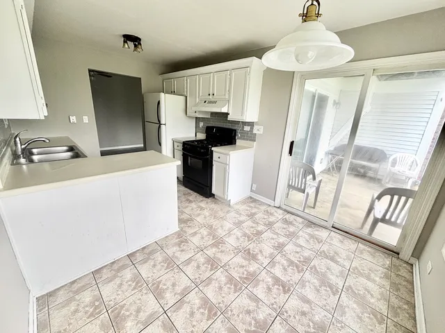 a kitchen with granite countertop a refrigerator and a stove top oven