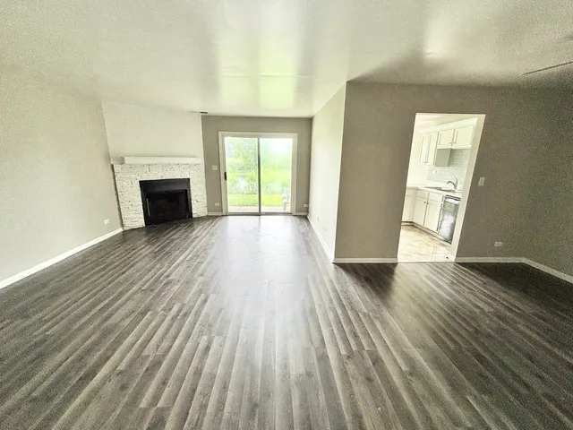 an empty room with wooden floor fireplace and windows