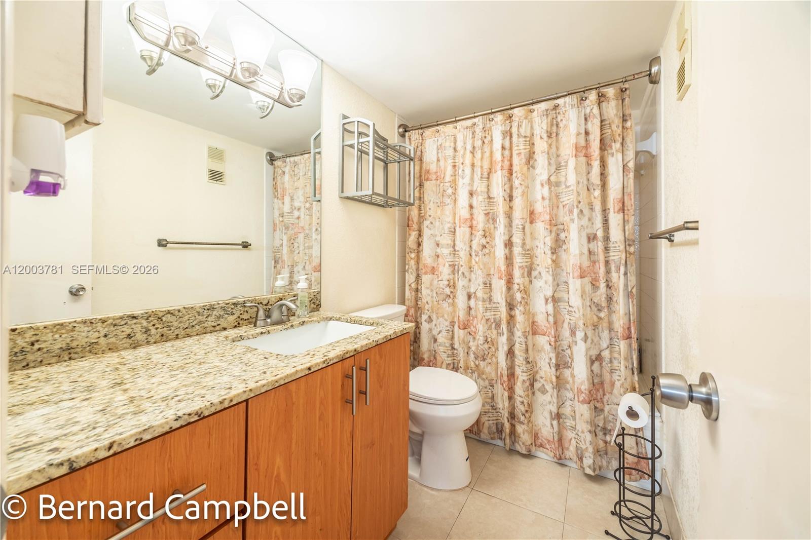 3940 Inverrary Boulevard, Unit 403A Lauderhill, FL 33319 - Photo 14 of 37 a bathroom with a granite countertop sink a toilet and shower curtain