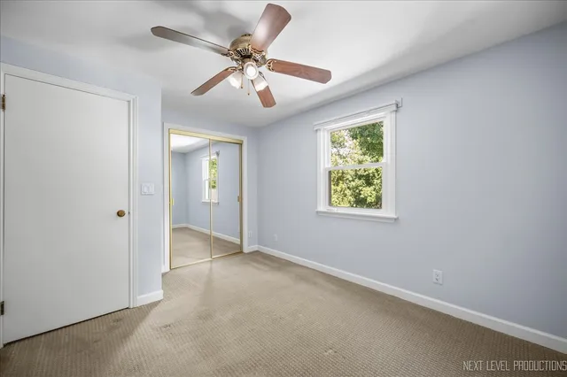 an empty room with chandelier fan and windows