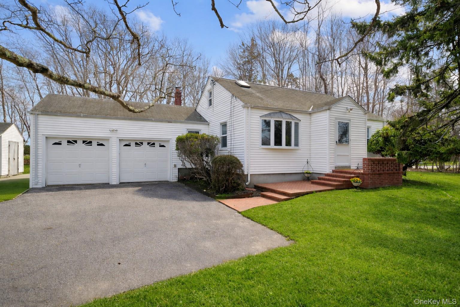 281 Woodacres Road East Patchogue, NY 11772 - Photo 2 of 11 Front view of house with 2 car attached garage.Green Grass Courtesy of AI.