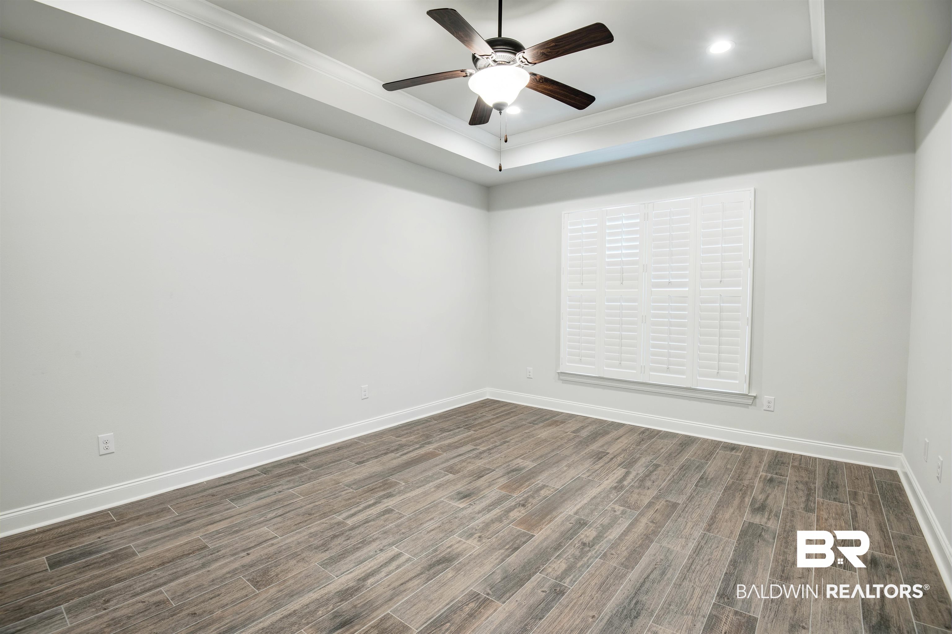 9843 Chipper Lane Foley, AL 36535 - Photo 15 of 34 Empty room with a tray ceiling, ornamental molding, dark wood-style floors, baseboards, and ceiling fan